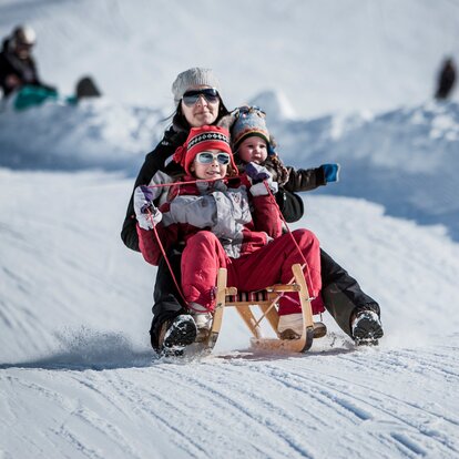 Mother with two children on a sledge during descent