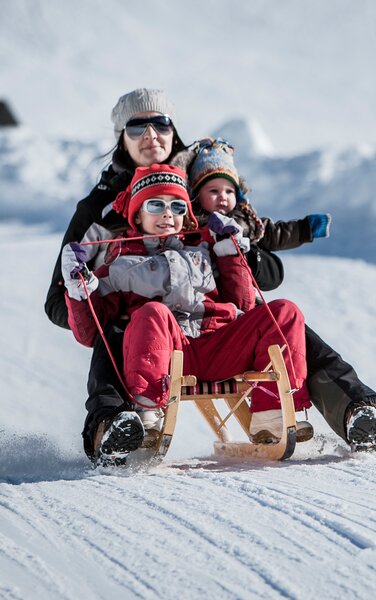 Mother with two children on a sledge during descent