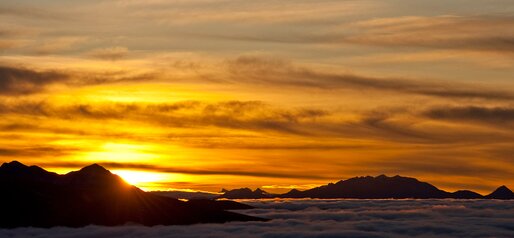 Wunderschöner gelbroter Sonnenaufgang oberhalb der Wolken