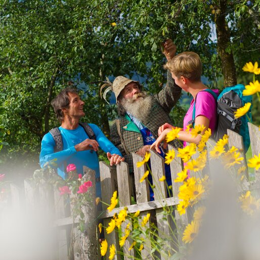 Due escursionisti con un pastore davanti a un recinto con fiori, in primavera | © Franz Gerdl