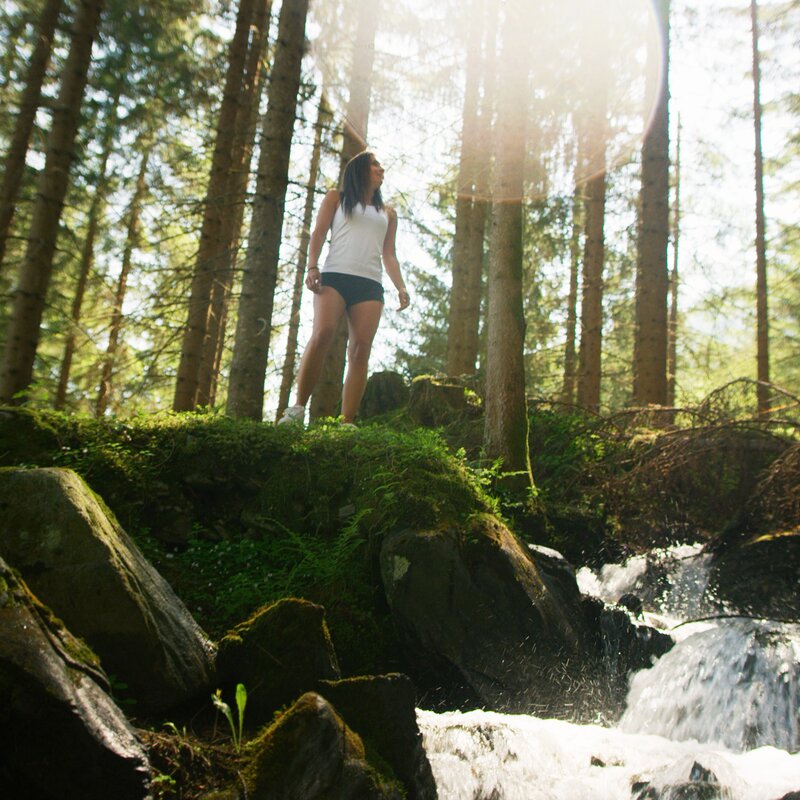 Frau neben kleinen Bach im Wald | © Rawmedia