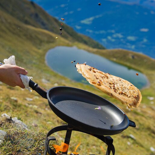 Kaiserschmarren wird in einer Pfanne in die Luft geworfen, oberhalb des Grünbachsees | © TV Kiens_Franz Gerdl
