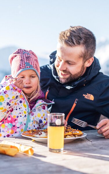 Vater und Tochter beim gemütlichen Mittagessen auf einer Skihütte