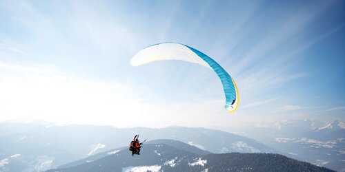 Ein Paragleiter im Winter oberhalb des Kronplatz-Gipfels. | © Tandemflights Kronplatz